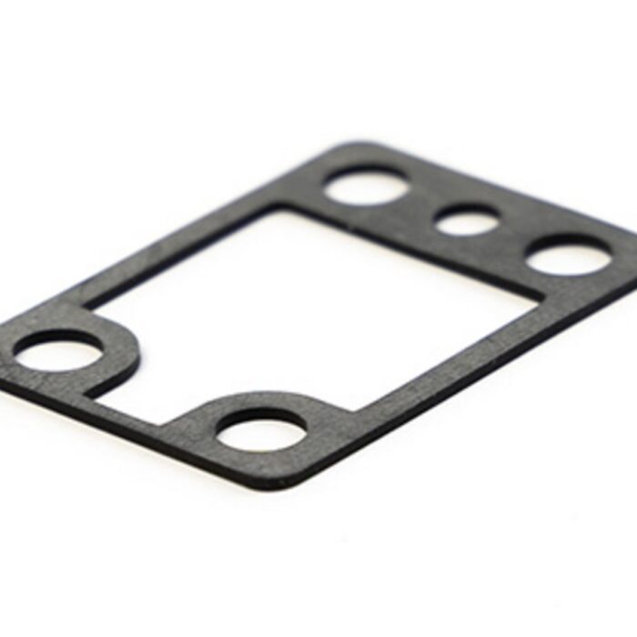 Gezeigt wird eine rechteckige Flachdichtung aus schwarzem Material, die über eine große zentrale Öffnung und fünf kleinere Bohrungen verfügt.