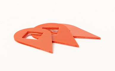 Drei orangefarbene, dreieckige Dichtungen aus Kunststoff mit einer rechteckigen Aussparung liegen als gefertigte Teile auf einem weißen Hintergrund.