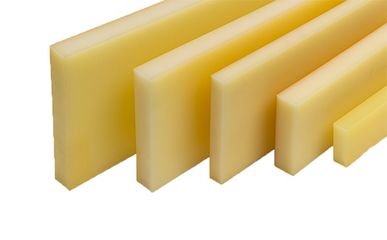 Mehrere massive Leisten aus gelblichem Kunststoff liegen in unterschiedlichen Breiten als fertig zugeschnittene Bauteile auf einem weißen Hintergrund.