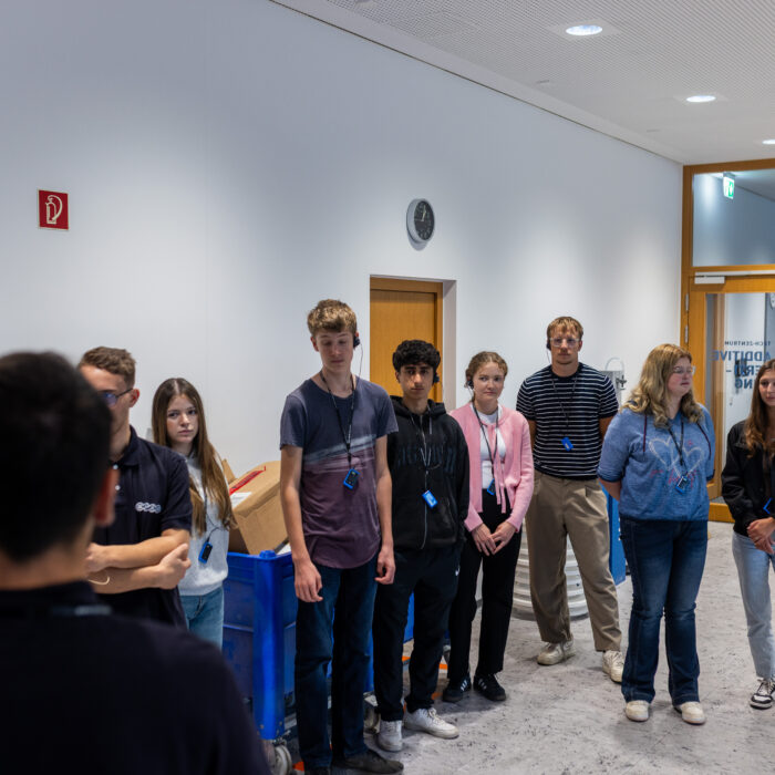 Eine Gruppe von Auszubildenden steht in der Additive Fertigung. 