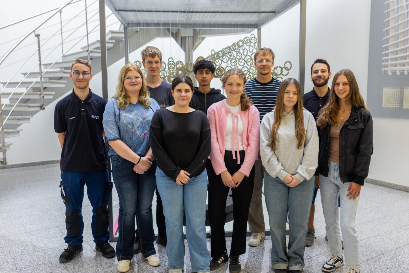 Ein Gruppenfoto vor der Treppe am Empfangsbereich aller neuen Auszubildenden zum Ausbildungsstart. 