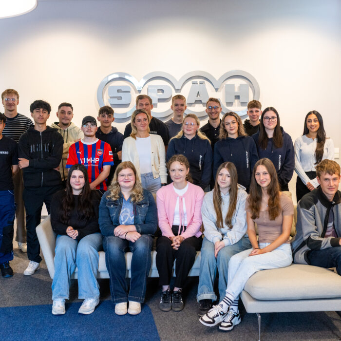 Gruppenfoto mit allen Auszubildenden bei dem alle Neuen auf dem Sofa sitzen und die älteren Auszubildenden hinter dem Sofa stehen.