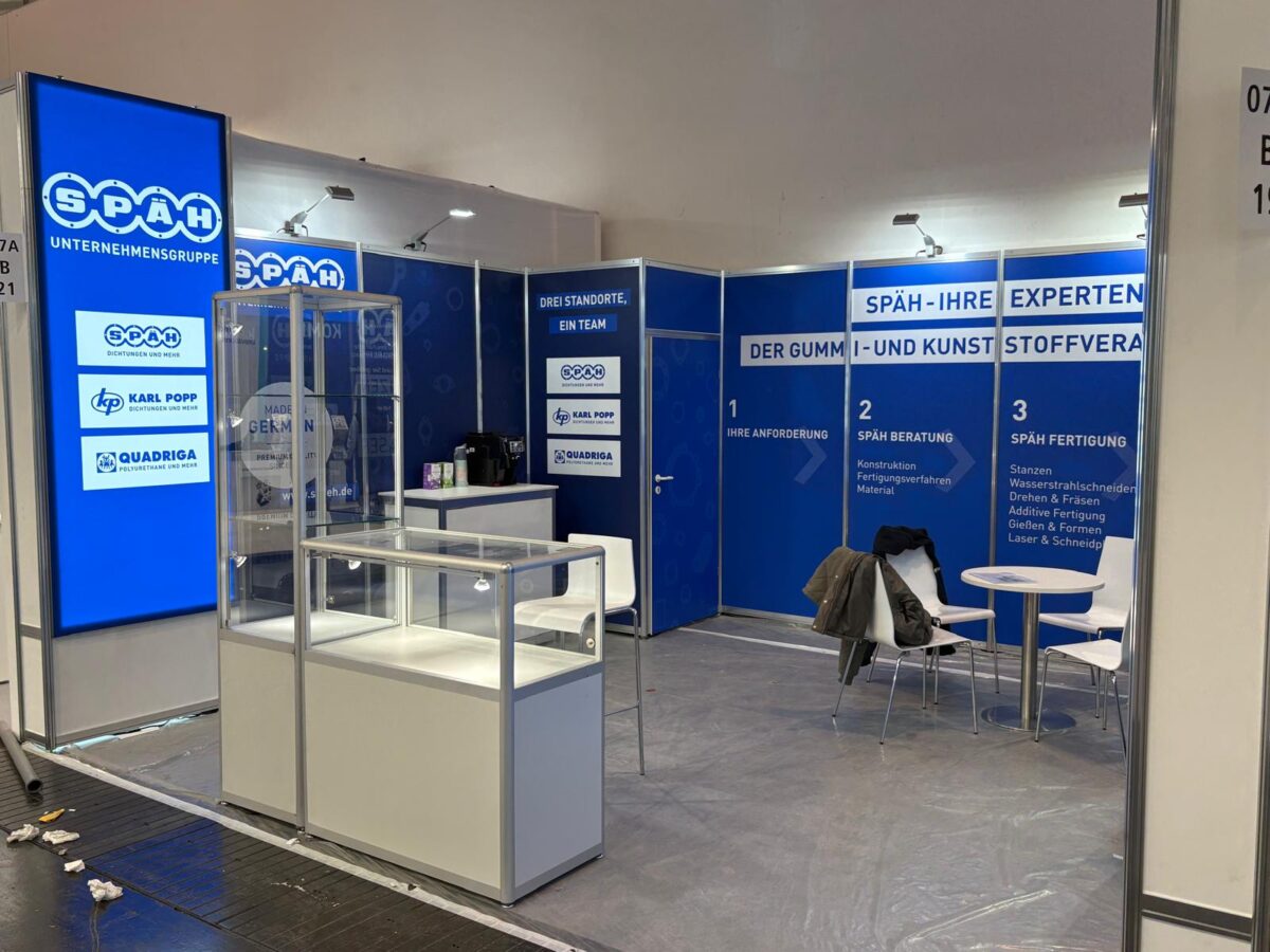 Späh Stand auf einer Messe. Zu sehen ist eine Vitrine, Wände mit Informationen und ein Tisch mit Stühlen. 