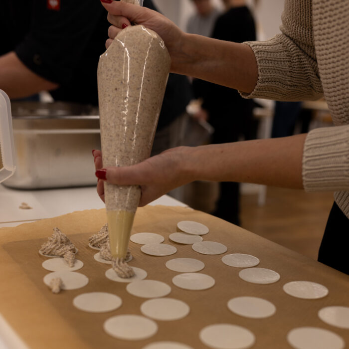 Eine Späh-Mitarbeiterin steht vor einem Backblech und gibt Spritzgebäck auf das Blech.