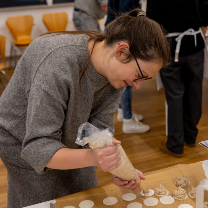 Eine Späh-Mitarbeiterin steht vor einem Backblech und gibt Spritzgebäck auf das Blech.